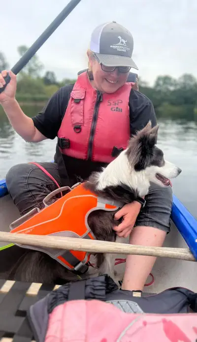 Trainerin Vanessa sitzt im Kanu mit Border Collie